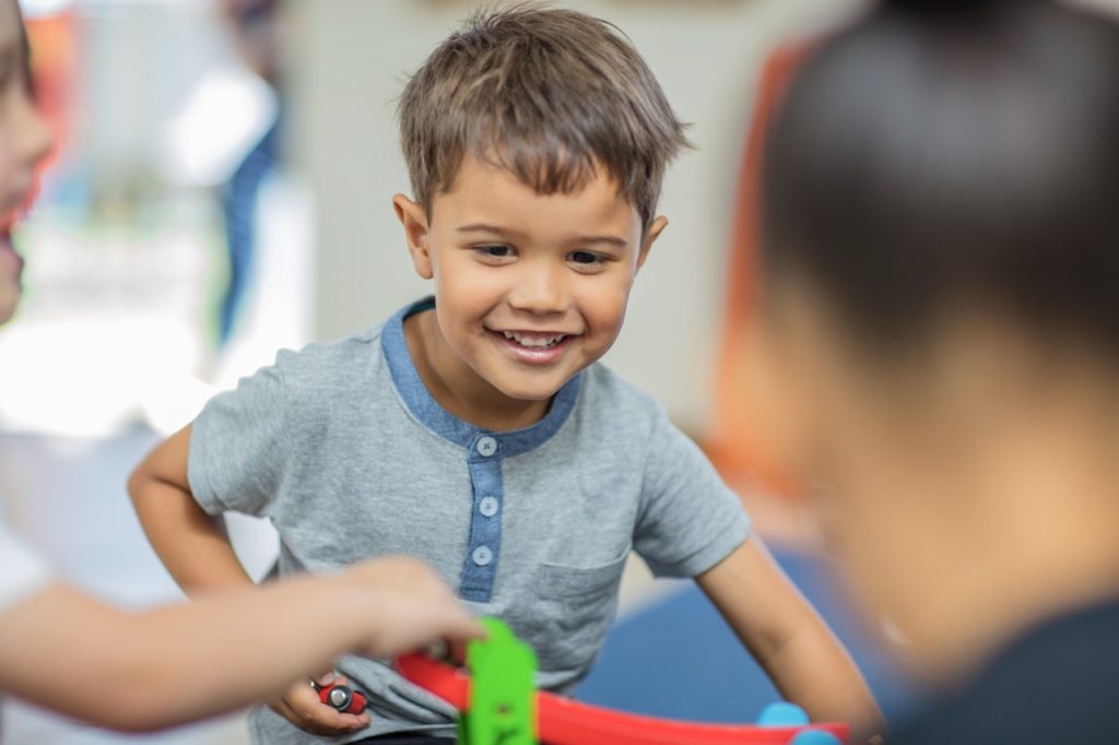 Happy boy playing with other children in kindergarten