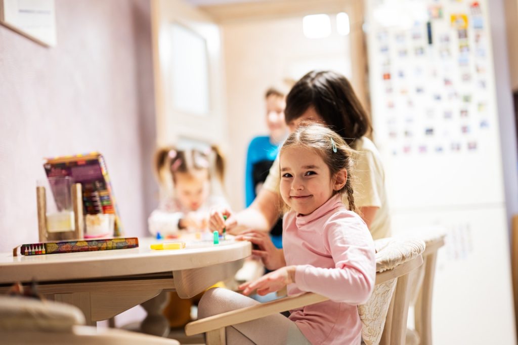 Mother and children decorating art with glitter decor.