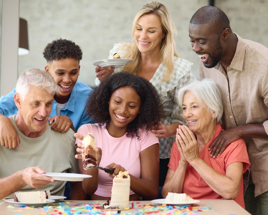 Three Generation Family Indoors At Home Celebrating Teenage Daughter's Birthday With Party And Cake
